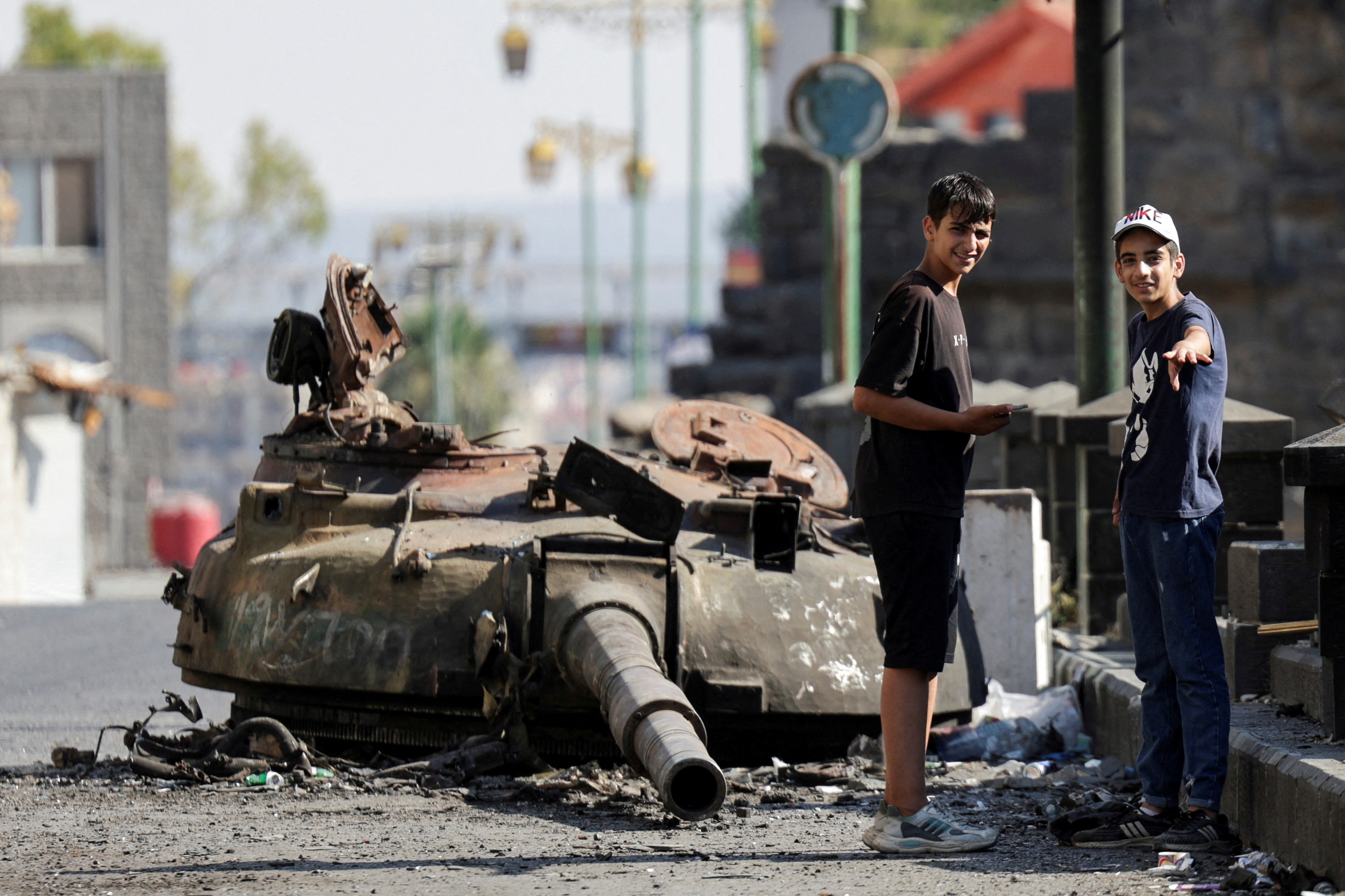 People stand next to a destroyed tank turret, following deadly clashes between Druze fighters, Sunni Bedouin tribes and government forces, in Syria's predominantly Druze city of Sweida, Syria July 25, 2025. (Reuters)