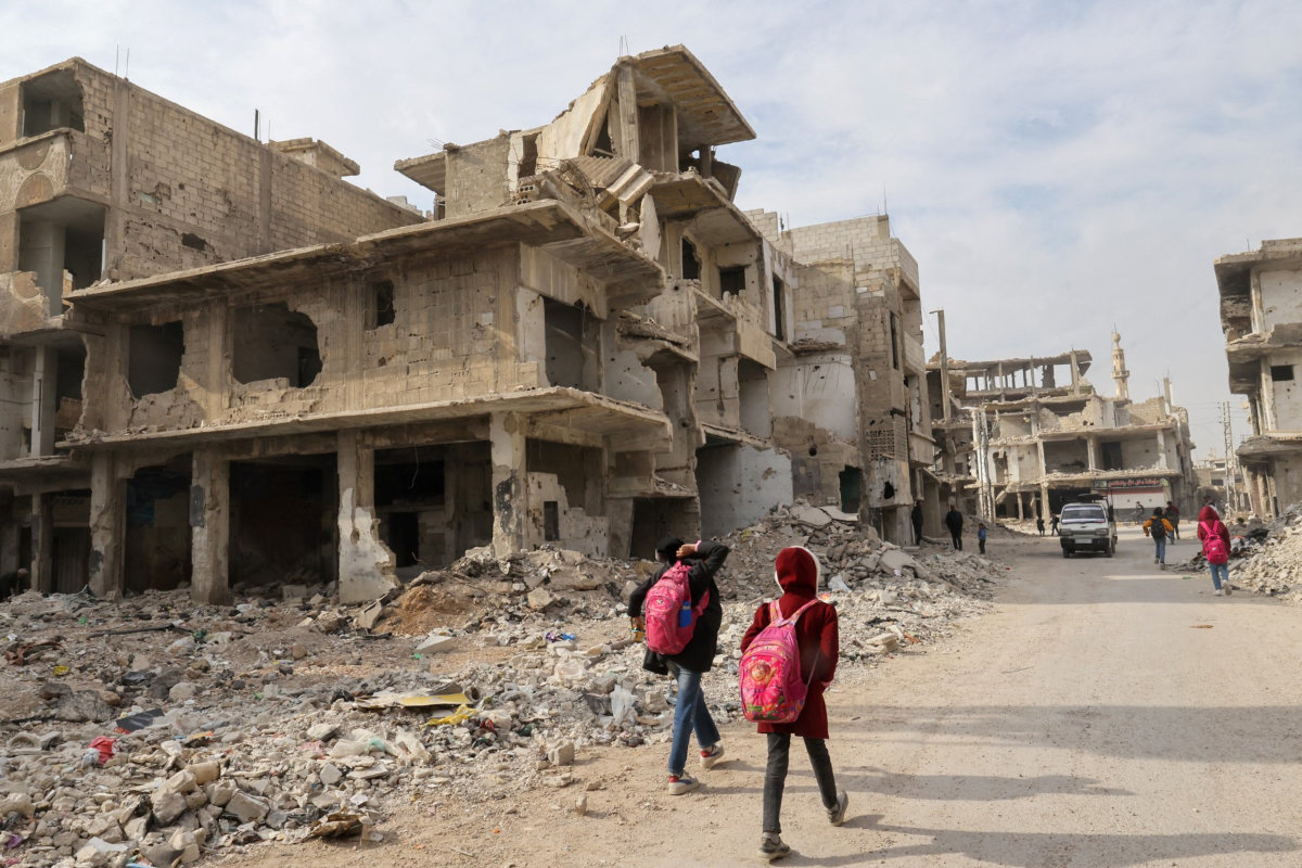 Children walk back from school past building rubble in the devastated Hajar al-Aswad area near the Yarmuk camp for Palestinian refugees on the southern outskirts of Damascus on December 23, 2024.