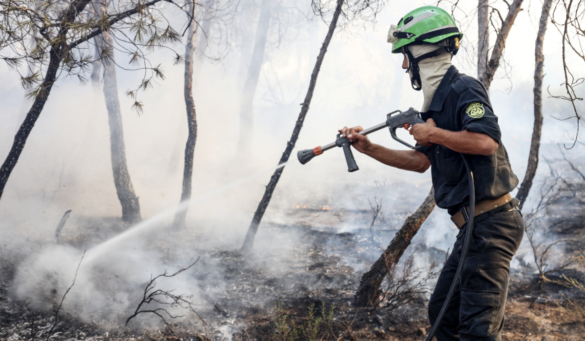 A member of a civil protection unit battles a wildfire in a mountainous area near the town of Al Hachimia, Bouira Province, on July 21, 2026. (AFP)