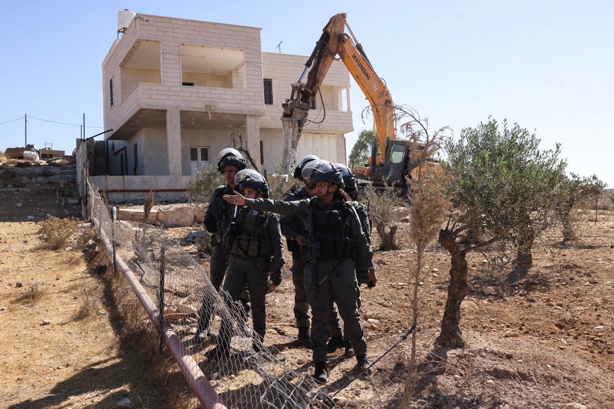 Israeli security forces stand guard beside a Palestinian house that was reportedly built without construction permits and is slated for demolition in the Israeli-occupied West Bank. (File/AFP)