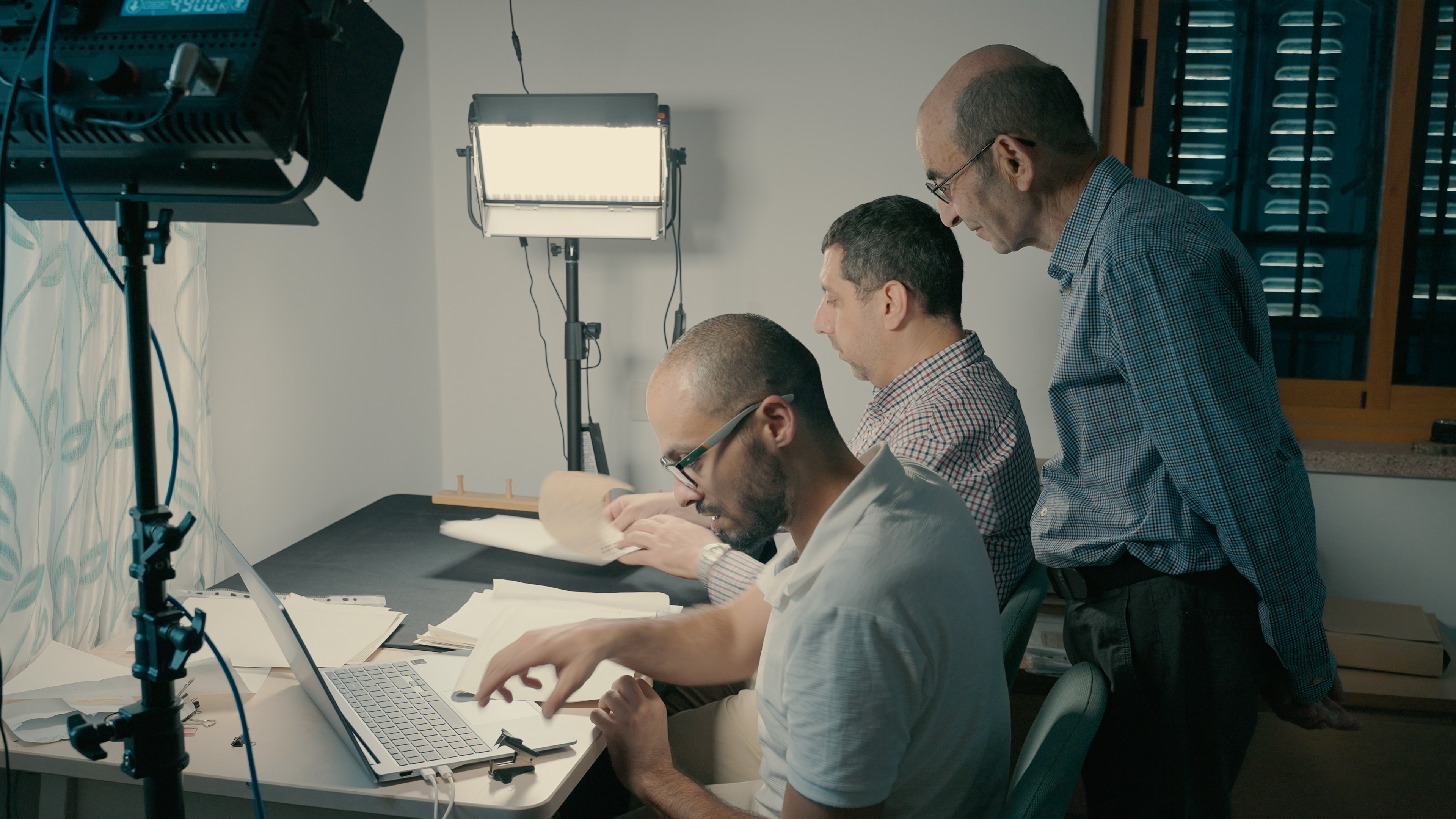 Yazeed Abu Khdeir (L) and Mahmoud Muna digitize papers as Shehadeh (R) looks on - Palestine, August 2025. (Hannah Harper)