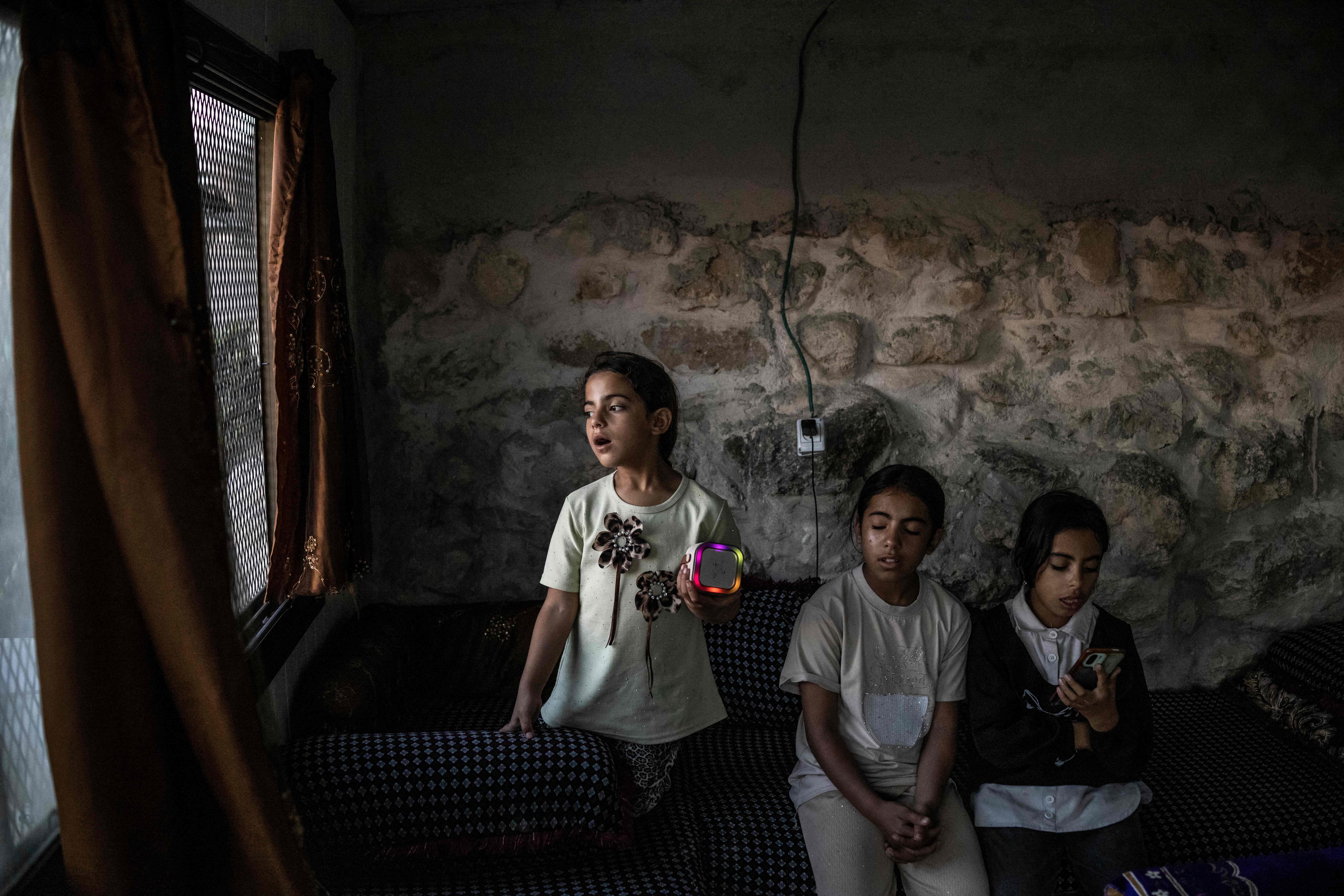 Palestinian sisters Layan (L), Bisan (C) and Ni'ameh sing karaoke inside the cave that their family has turned into their home in the village of Al-Tuwani, in the Israeli-occupied West Bank. (AFP)