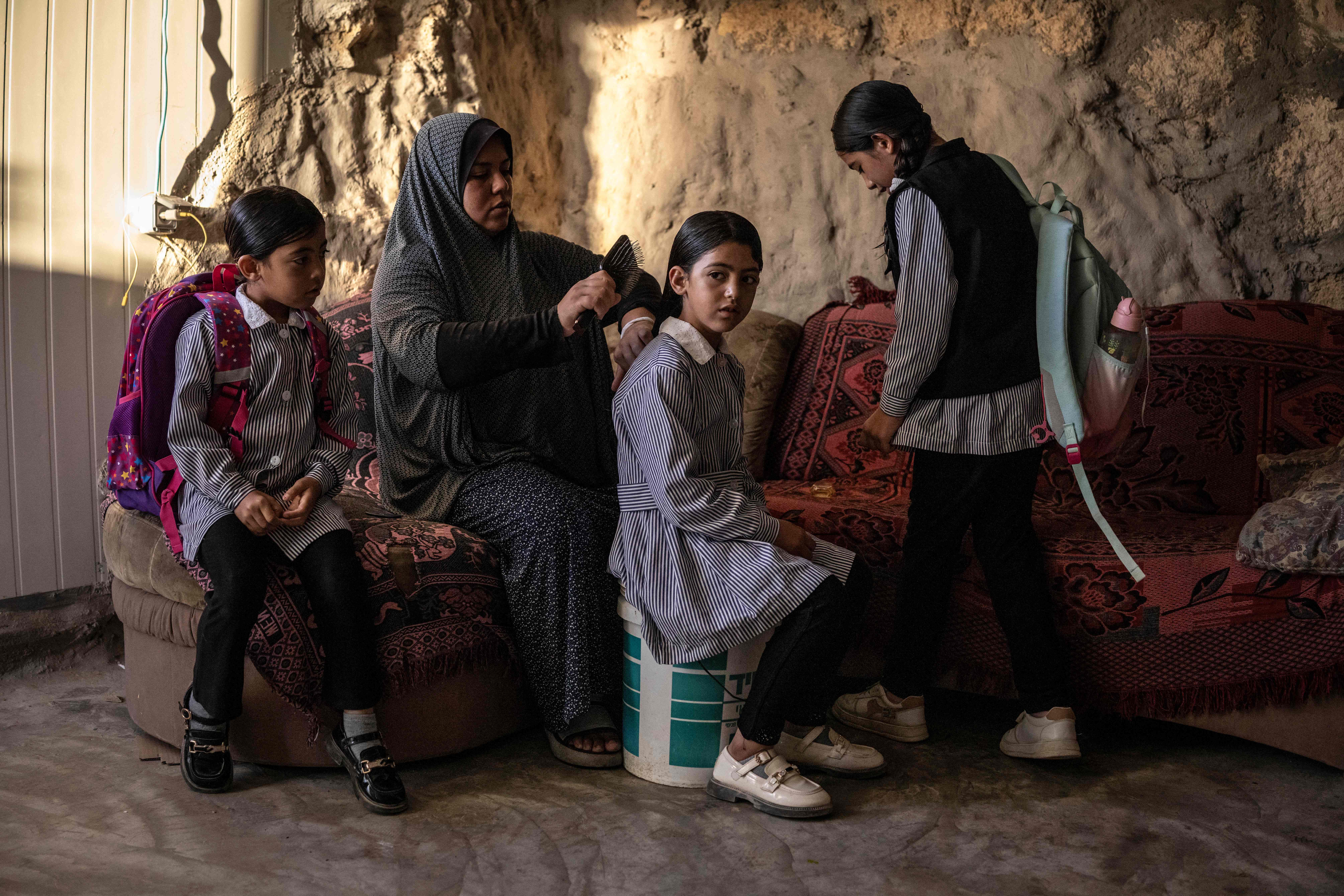 Arwa Amr brushes her daughter Layan's hair as they prepare for school inside the cave that the family has turned into their home in the village of Al-Tuwani, in the Israeli-occupied West Bank. (AFP)