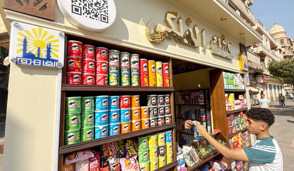 A customer grabs items from one of the newly introduced unified-design kiosks on the sidewalk of a street in downtown Cairo on September 18, 2026. (AFP)