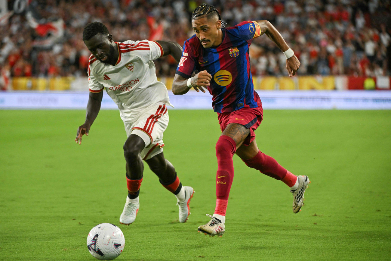 Sevilla's Senegalese defender #12 Arouna Sangante (L) and Barcelona's Brazilian forward #11 Raphinha fight for the ball during the Spanish league football match between Sevilla FC and FC Barcelona at the Ramon Sanchez Pizjuan stadium in Seville on September 19, 2026. (AFP)