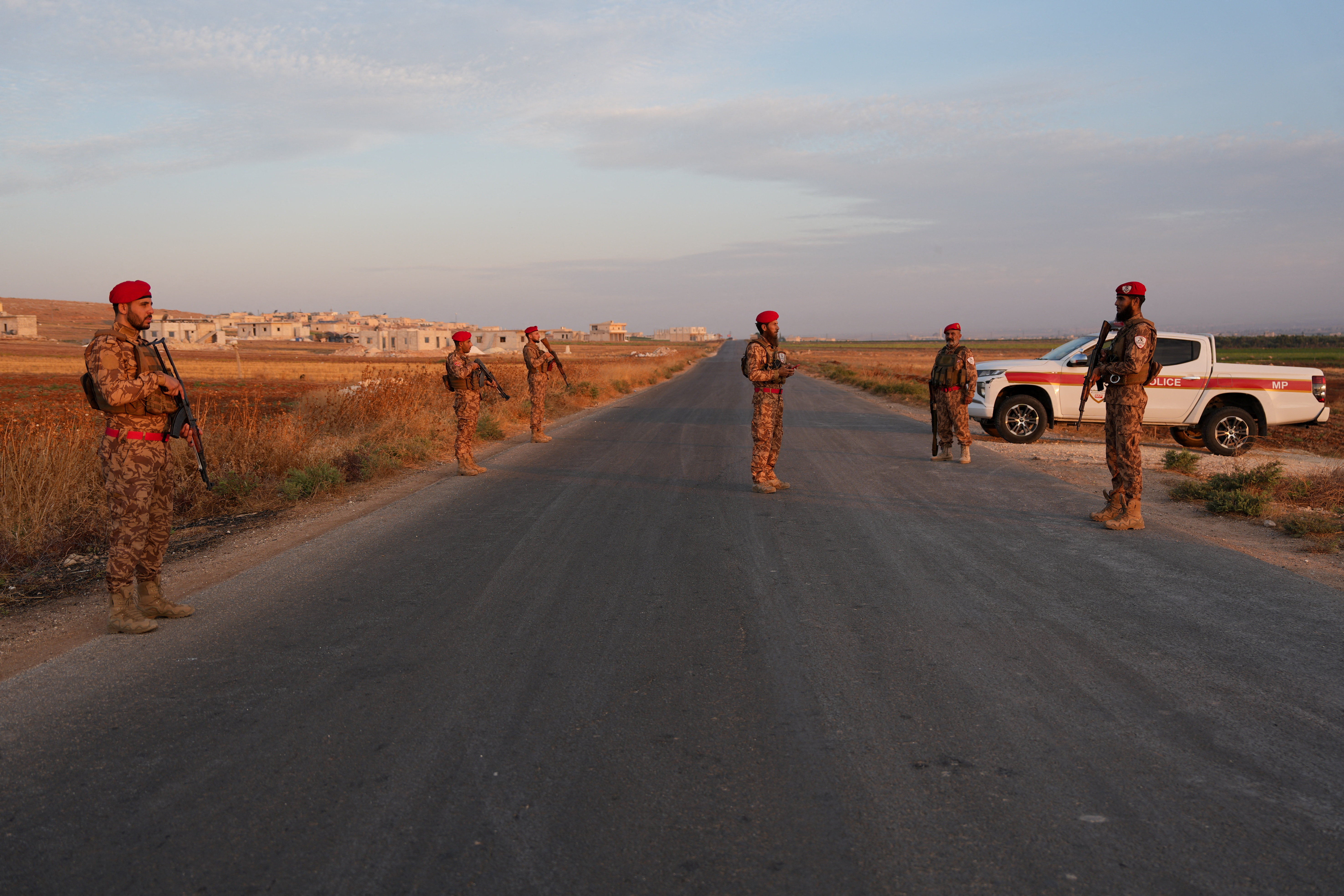 Military police officers stand along a road following an explosion at a weapons depot in the Al-Eis area, in the southern countryside of Aleppo, Syria, September 21, 2026. (Reuters)