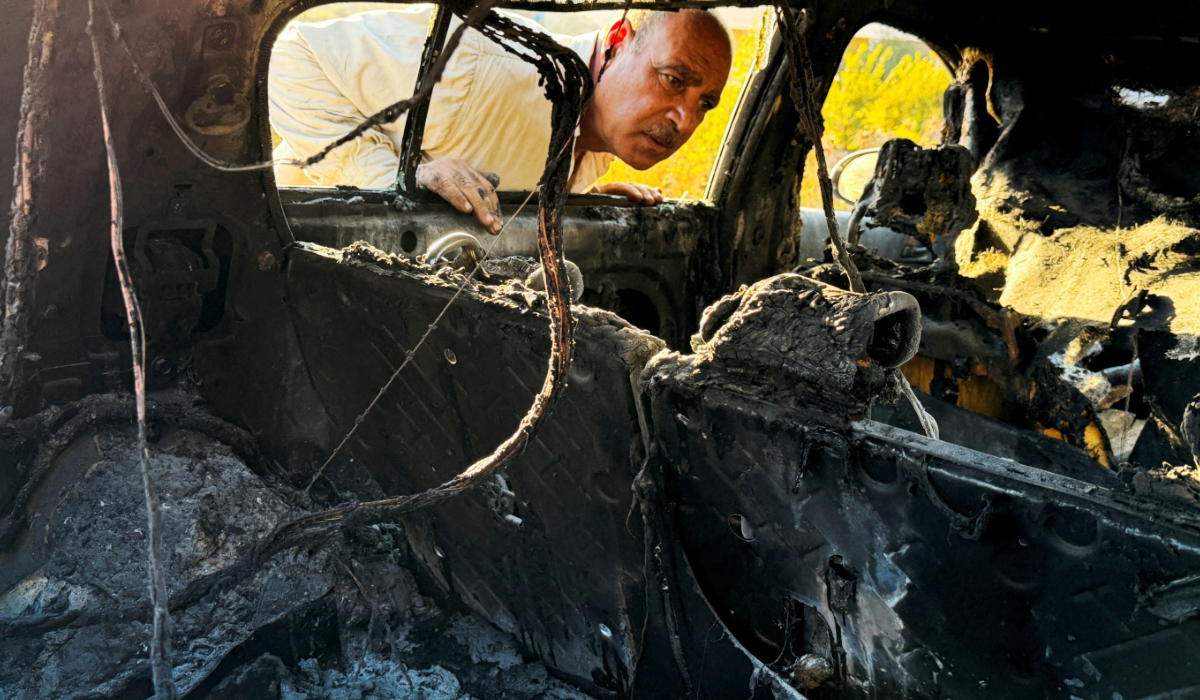 A man inspects a damaged car, which Palestinians say was burned by Israeli militant settlers, near Hebron in the Israeli-occupied West Bank, September 20, 2026. (REUTERS)