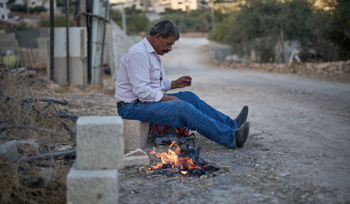 Wajeeh Hamdan sits next to the fire in front of his house in the West Bank village of Burqa, Thursday, Sept. 17, 2026, as his wife is recovering at home after she was hit during an attack by Israeli settlers last month. (AP)