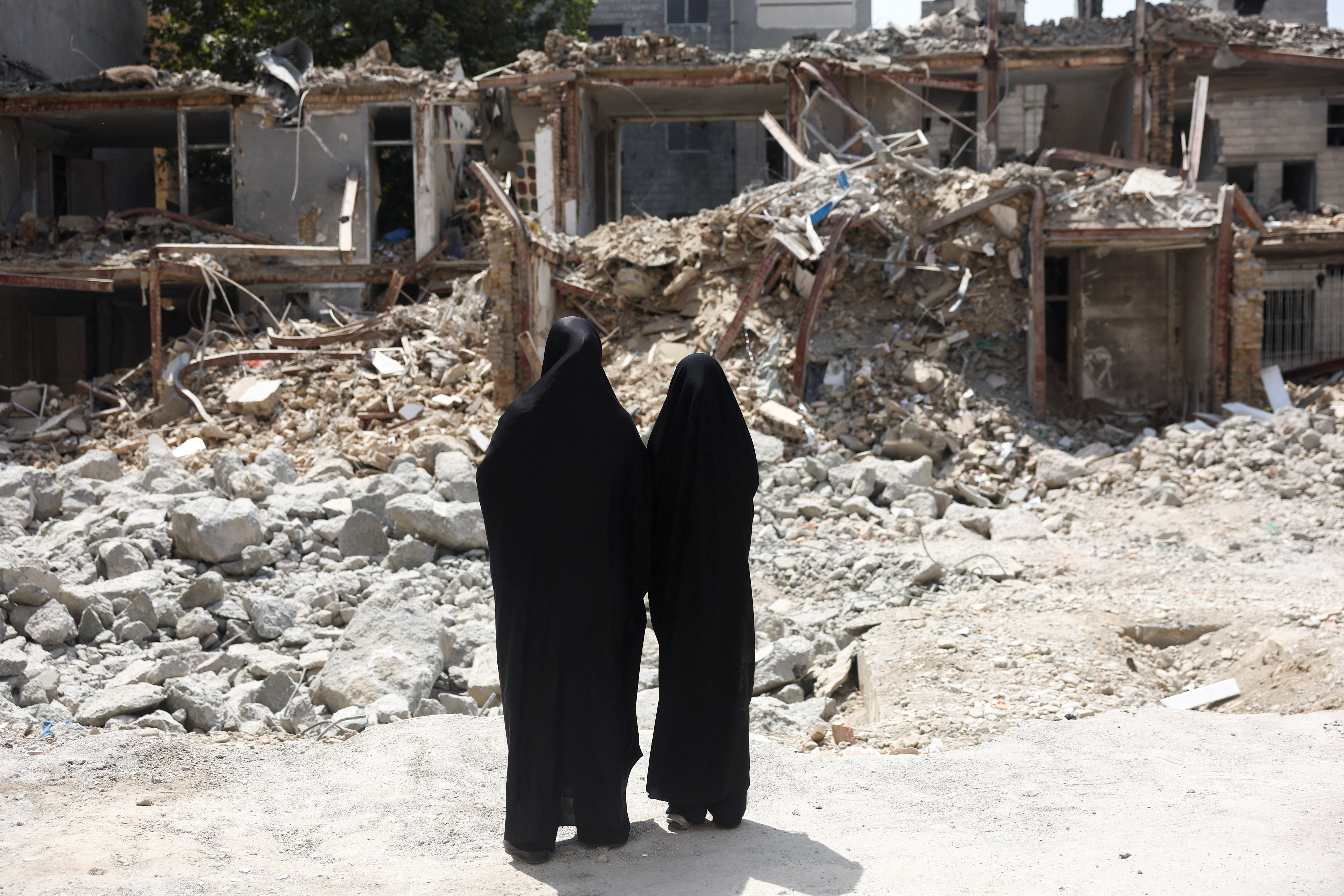 Iranian women look at a building, which was damaged in a US and Israeli strike in March, in Tehran, Iran, August 22, 2026. Reuters file