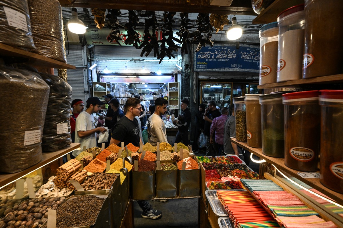 Shoppers stroll past a stall selling sweets and spices at the old market in Damascus ahead of the Eid Al-Adha holiday on May 26, 2026. (AFP)