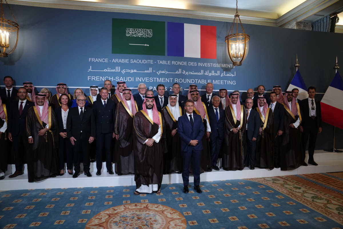 French President Emmanuel Macron and Saudi Crown Prince Mohammed bin Salman stand with delegates at the French-Saudi Investment Roundtable Meeting.