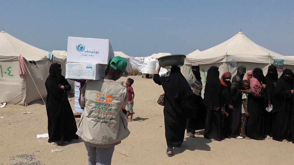 An aid worker carries foodstuffs during aid distribution to people, who fled fighting between the Houthis and Yemeni government forces in Red Sea coastal areas, at a camp for internally displaced people near Aden on September 23, 2026. (REUTERS)