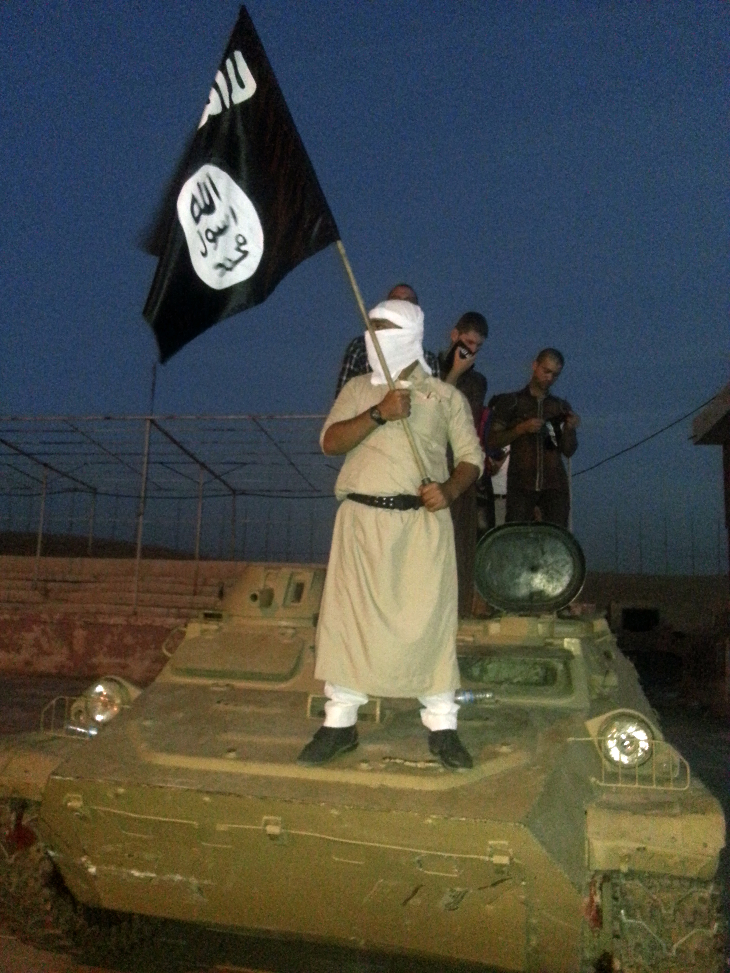 A Daesh fighter holds a flag while standing on an armored vehicle in Mosul. (Reuters file)