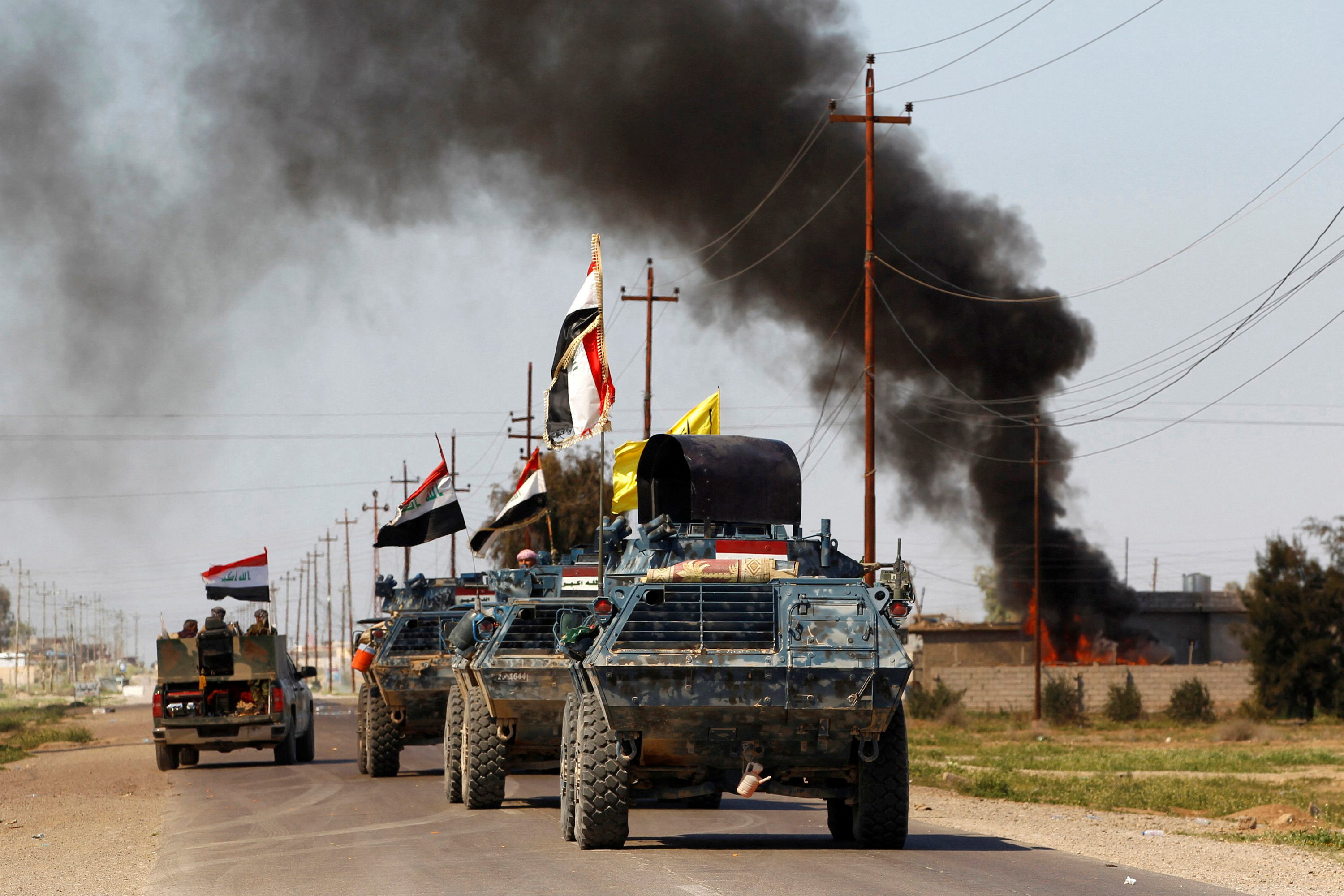 Hashid Shaabi fighters drive past smoke arising from a clash with Daesh militants on March 10, 2015. (Reuters file)