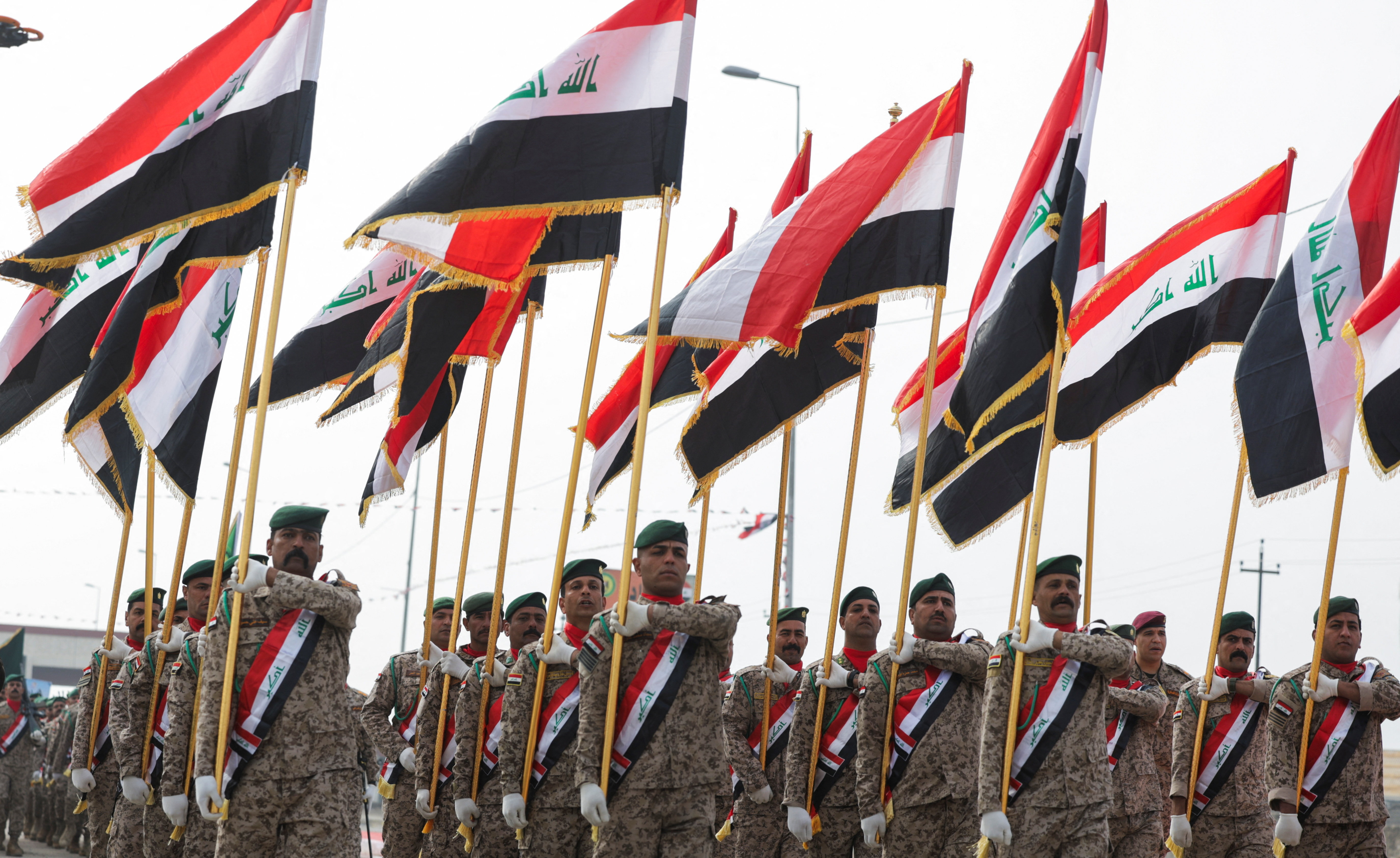 Iraqi soldiers carry national flags during a military parade marking the eighth anniversary of defeating Daesh. (Reuters file)