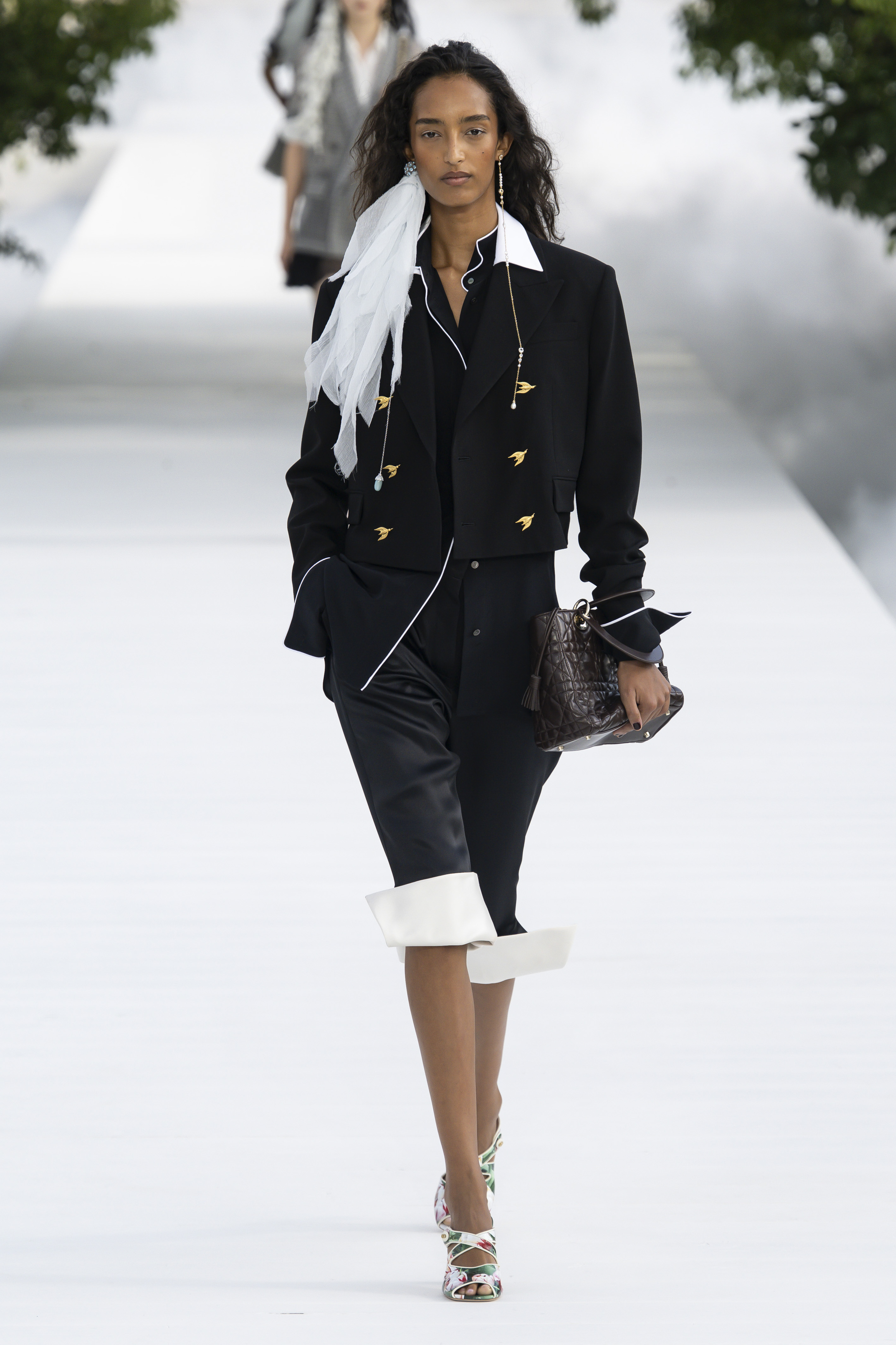 Danish model Mona Tougaard wore a a cropped black double-breasted jacket with gold bird-shaped buttons over a white-piped shirt and satin skirt, finished with a sheer white scarf. (Getty Images)