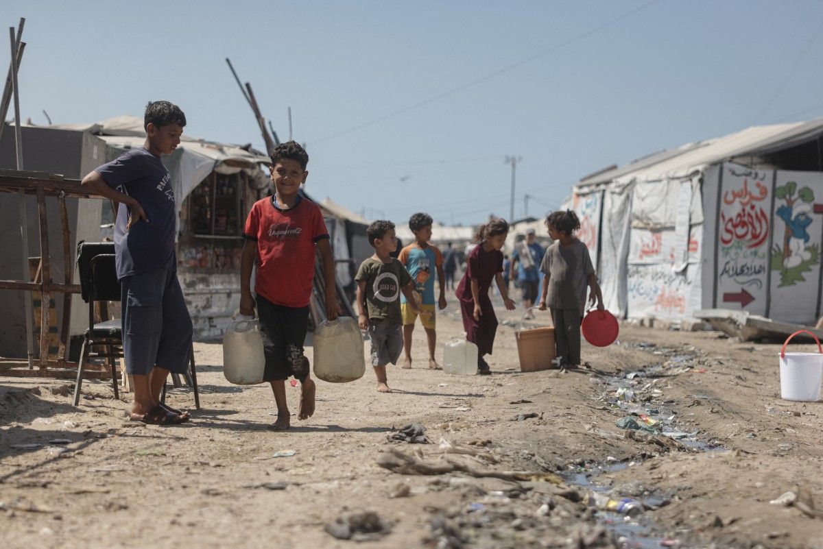 Palestinian children carry water jerrycans past the tents of displaced Palestinians in Al-Mawasi area of Khan Yunis in the southern Gaza Strip on Sept. 25, 2026. (AFP)