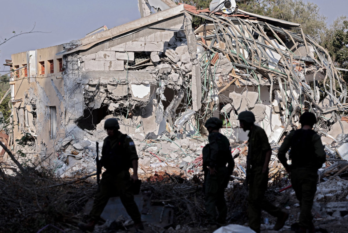 Israeli soldiers walk past a house destroyed in the October 7 attack by Palestinian Hamas militants on kibbutz Beeri near the border with Gaza, on October 14, 2023. (AFP/File)