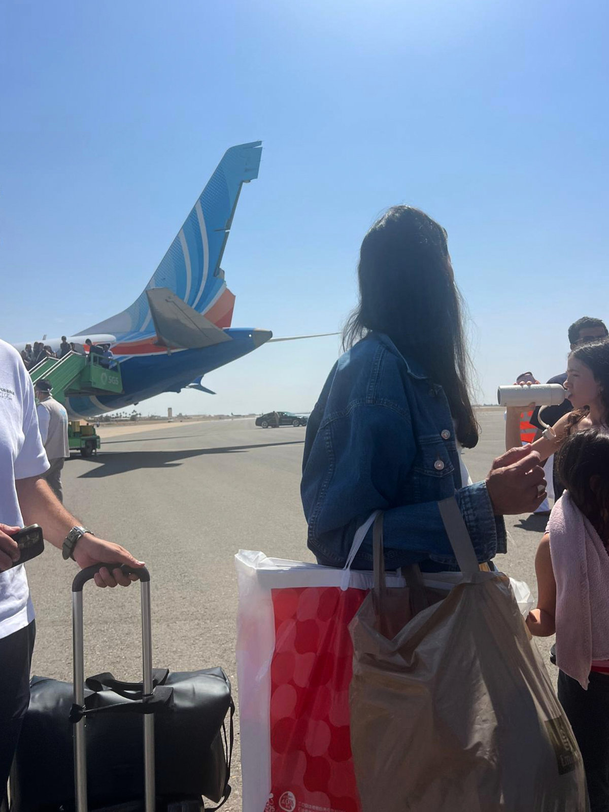 Passengers stand beside Flydubai Flight FZ1073, with damage visible to the aircraft’s tail, after it made an emergency landing at Prince Sultan bin Abdulaziz International Airport in Tabuk, Saudi Arabia, on Sept. 30, 2026. (AP Photo)