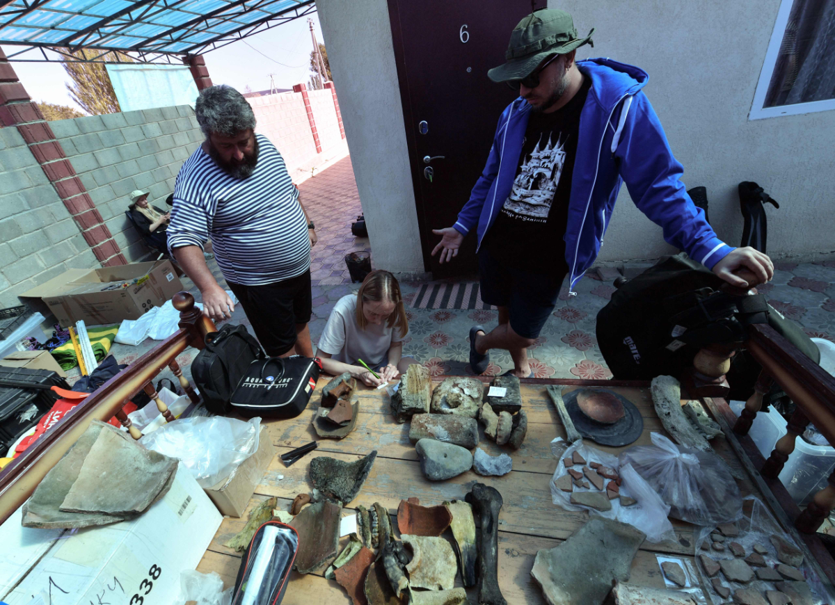 Expedition Director Maxim Menshikov and colleagues stand by artifacts found at the underwater site on the bed of Lake Issyk-Kul of what is identified by researchers as a submerged medieval city on the Silk Road in the settlement of Toru-Aygyr in Kyrgyzstan on September 22, 2026. (Photo by Vyacheslav Oseledko/ AFP)