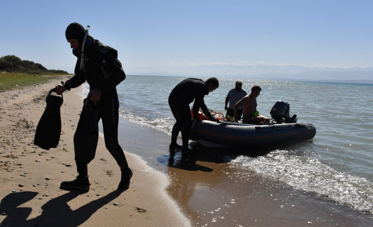 Maxim Menshikov, archaeologist and the expedition director, and divers go onshore with the finds discovered at the underwater site on the bed of Lake Issyk-Kul in Kyrgyzstan on September 22, 2026. (Photo by Vyacheslav Oseledko/ AFP)