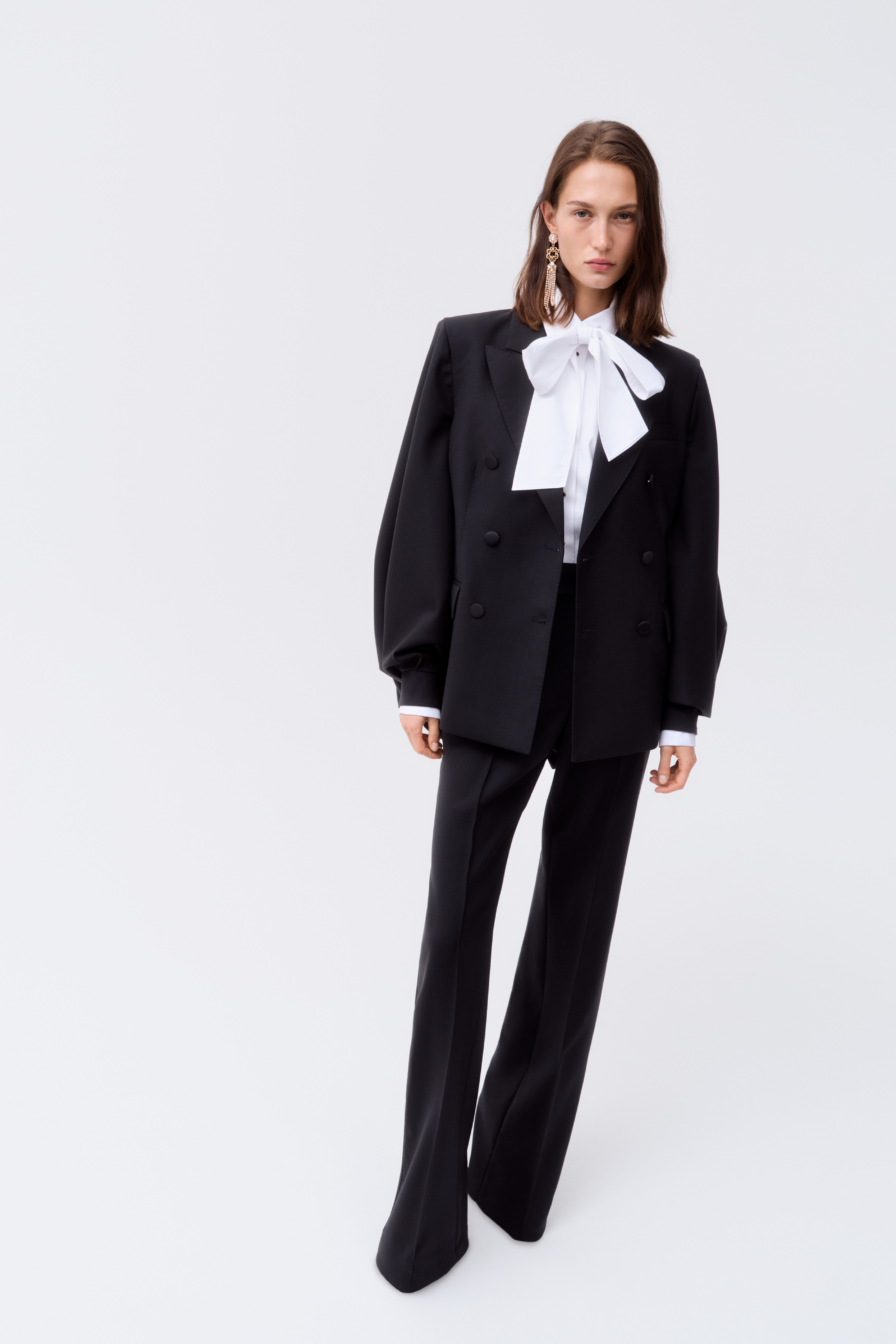 The classic black suit elevated by a dramatic white bow and statement accessories is from Elie Saab's collection with Swedish high-street retailer H&M. (Supplied)