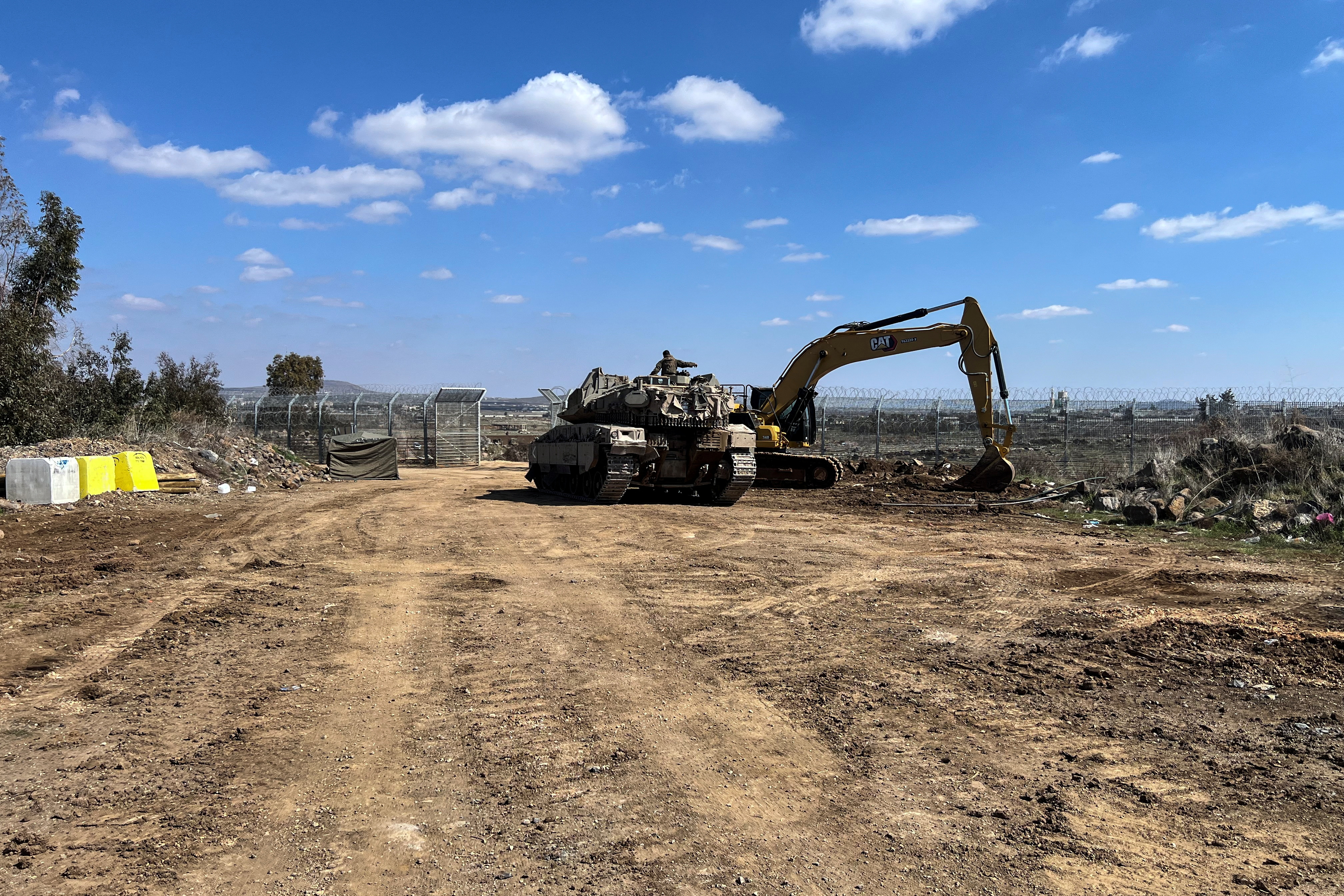 An Israeli military bugger and a tank are positioned by the fence of the ceasefire line by Syria and the Israeli-occupied Golan Heights, near Quneitra crossing in the Golan Heights, on its Israeli side March 2, 2025. (REUTERS/Avi Ohayon)