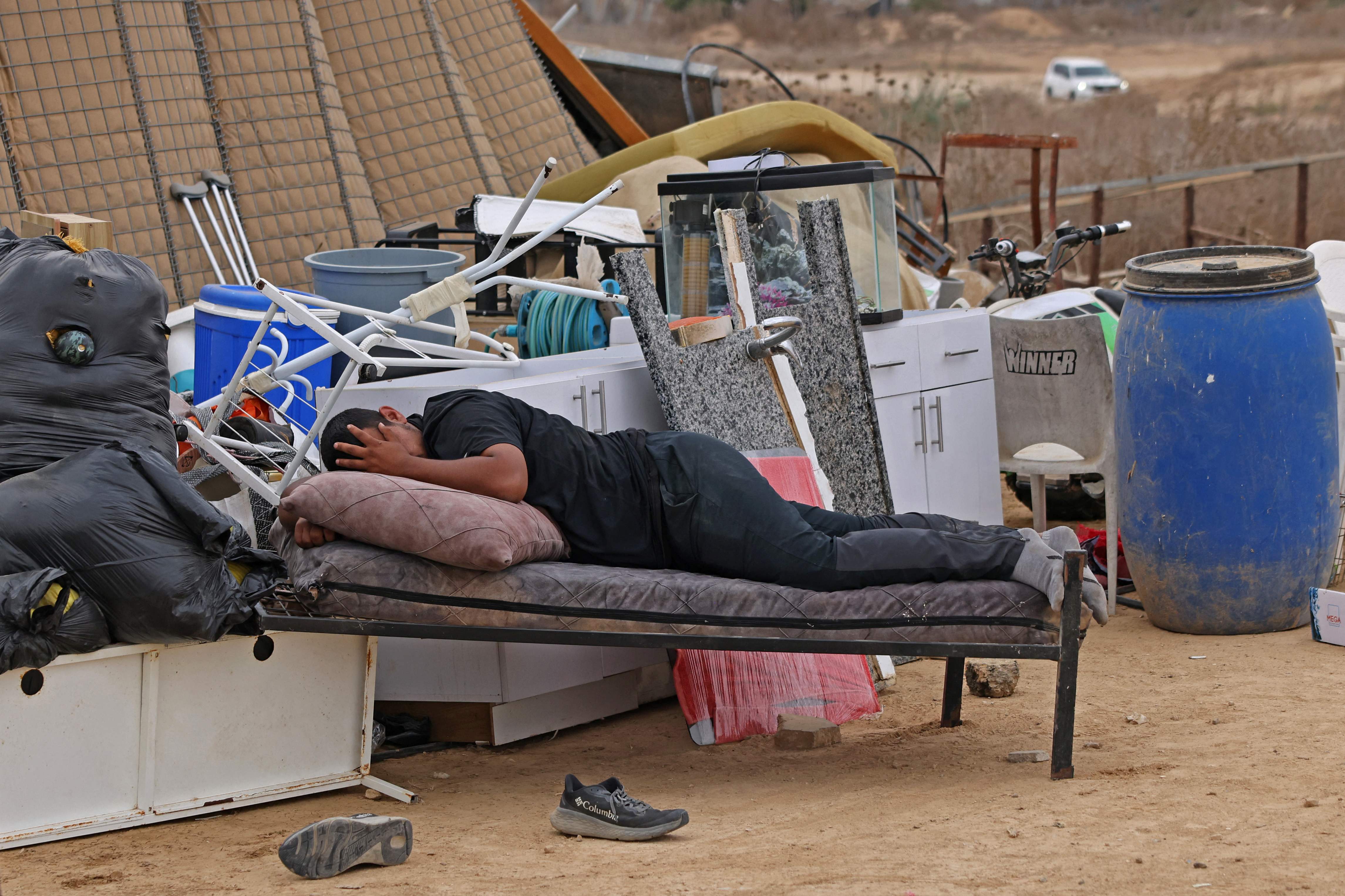 A man lies on a bed next to other items that were salvaged from the demolition of buildings of the Abu Wadi Bedouin, for lack of construction permits, in the village of al-Dhahiyah near Rahat in Israel's southern district on October 12, 2026. (AFP)