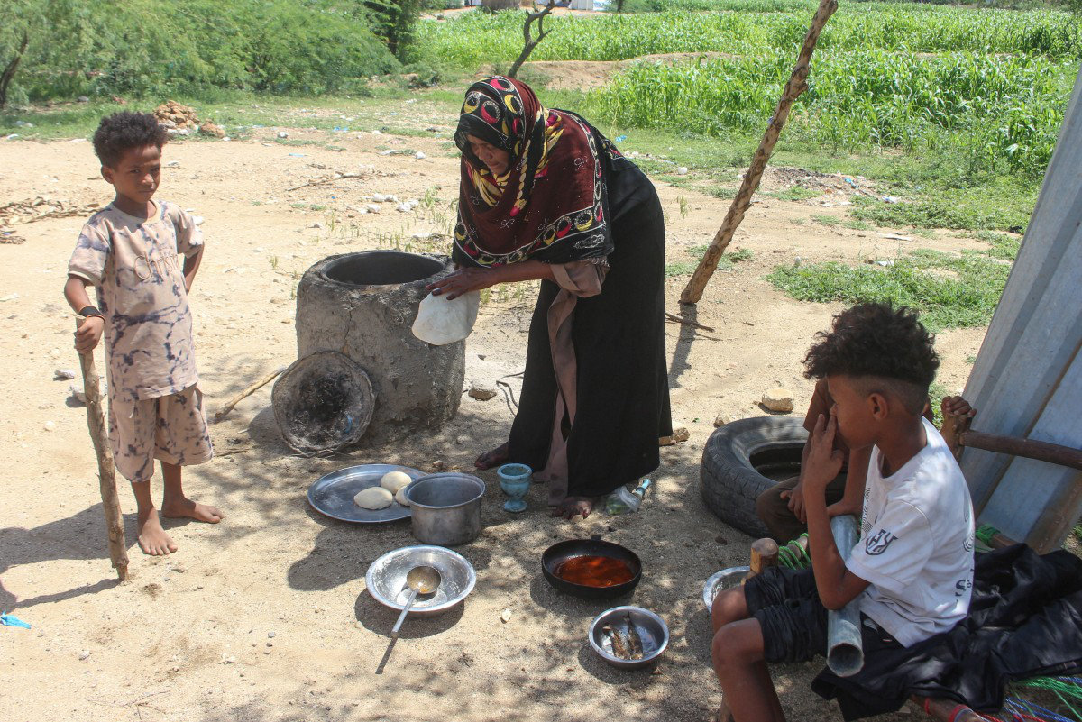 A Yemeni woman cooks a meal for her children at a makeshift camp for people fleeing renewed clashes between Yemen’s government forces and the Houthi militia in the northern Hajjah governorate on October 7, 2026. (AFP)