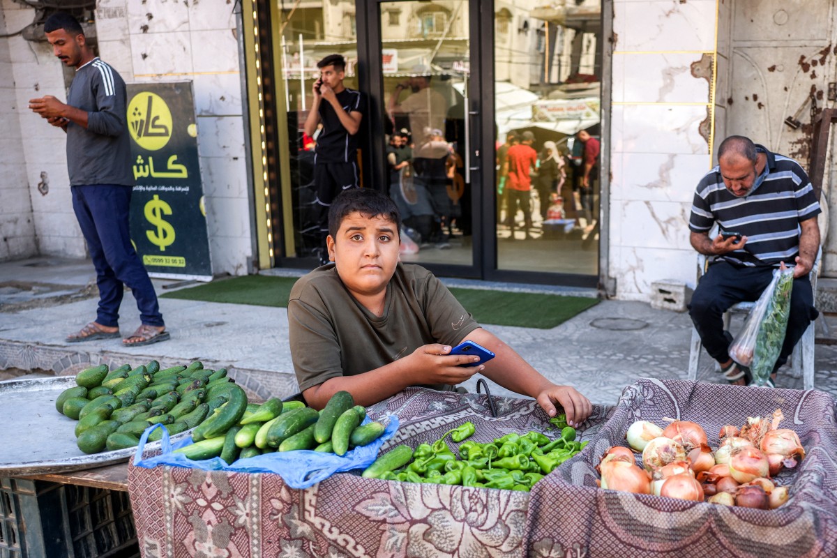 A young vendor sells cucumbers, peppers, and onions at a market in the Jabalia camp for Palestinian refugees in the northern Gaza Strip on October 19, 2026. (AFP)