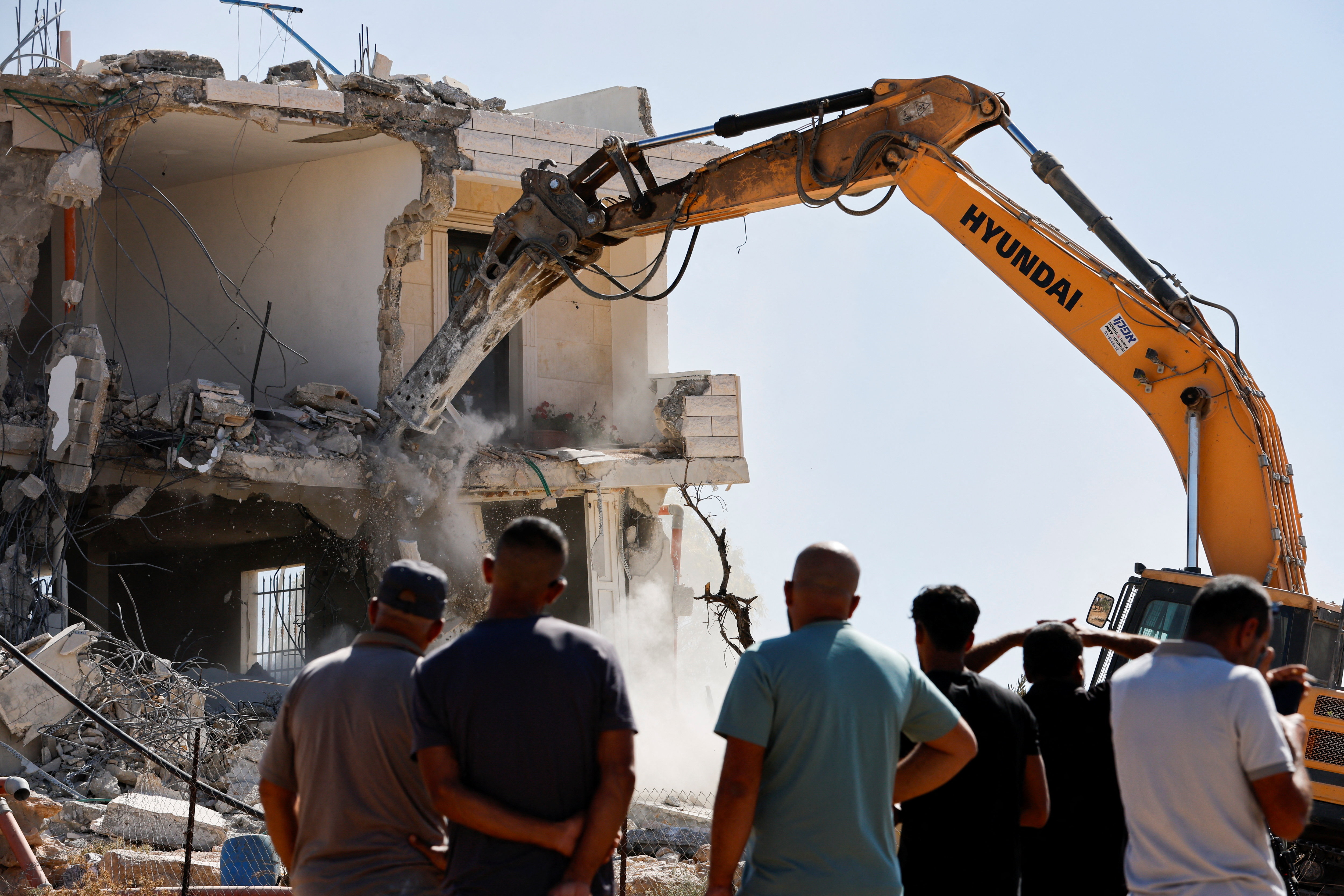 Palestinians watch as Israeli machinery demolishes a building near Hebron in the occupied West Bank, Sept. 16, 2026. (Reuters/Mussa Qawasma)
