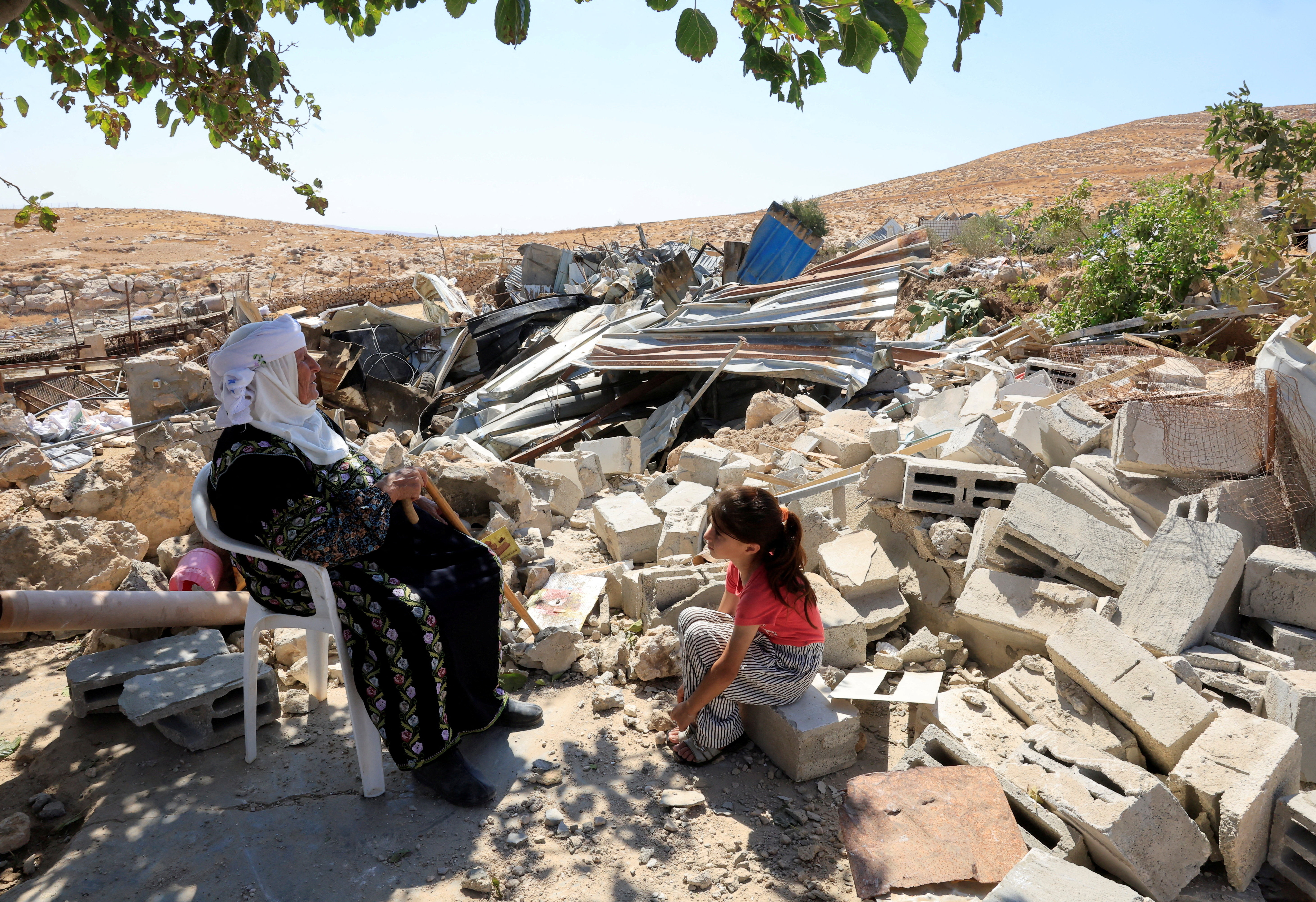 A Palestinian woman and a child sit amid the rubble after Israeli heavy machinery demolished homes in Jinba village in Masafer Yatta, near Hebron, in the Israeli-occupied West Bank, September 23, 2026. (REUTERS/Mussa Qawasma)