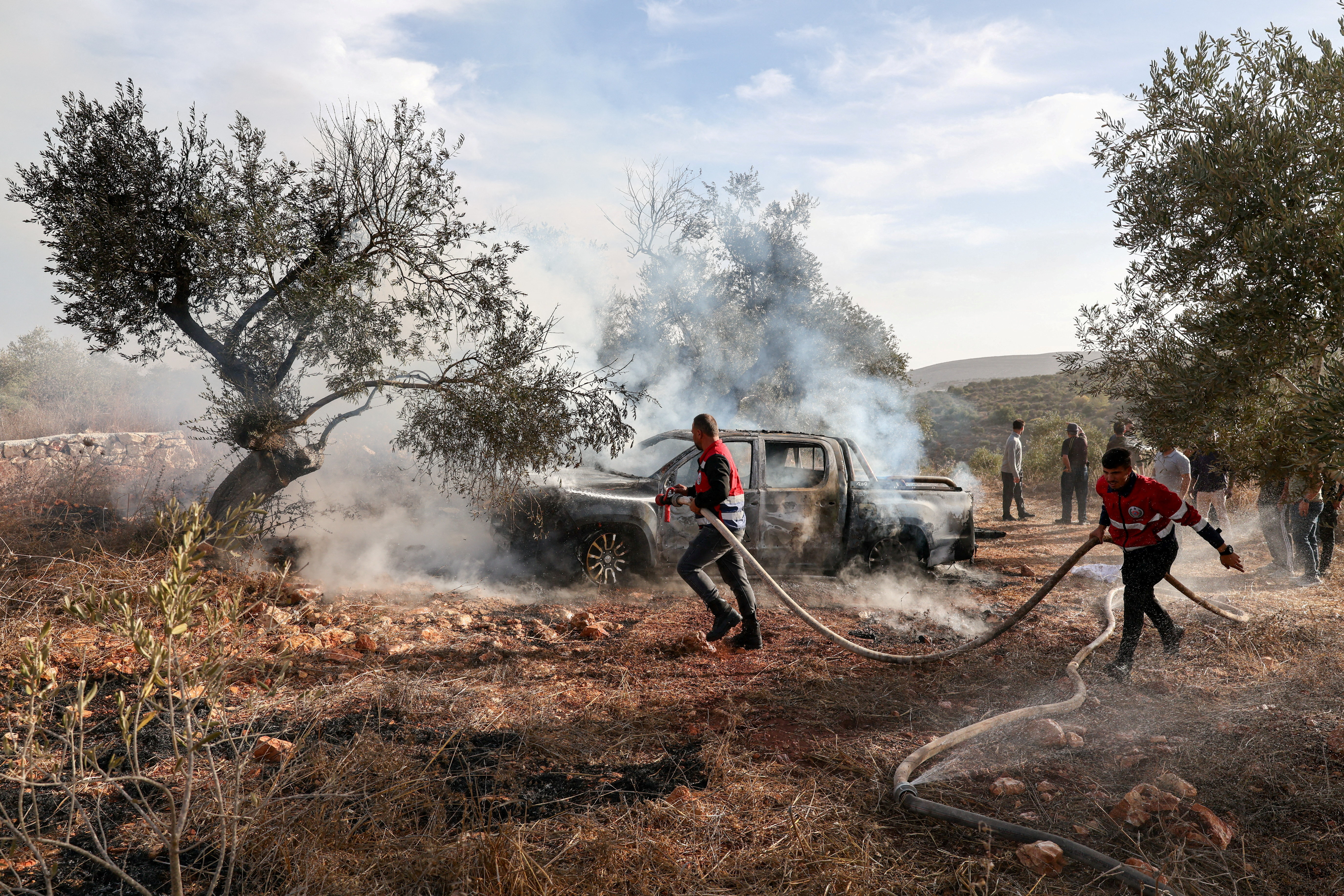 Firefighters extinguish a vehicle torched during a settler attack on Palestinian olive harvesters near Turmus Ayya, occupied West Bank, Oct. 16, 2026. (Reuters/Ammar Awad)