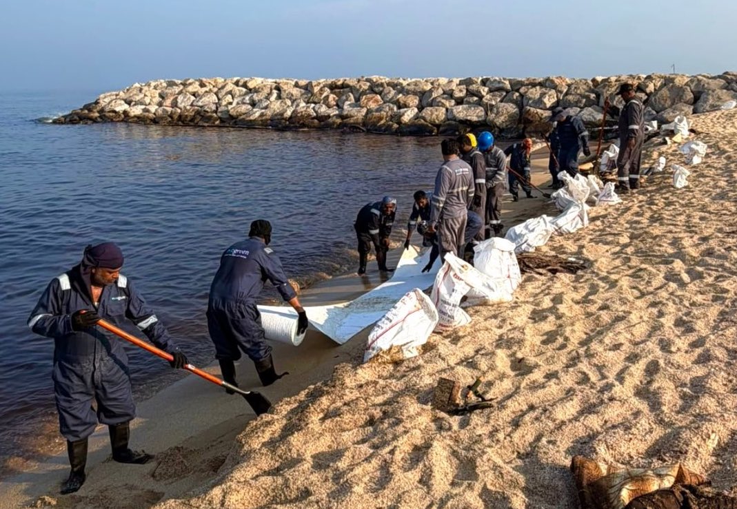 Workers clean a beach affected by an oil spill in Umm Al-Quwain.