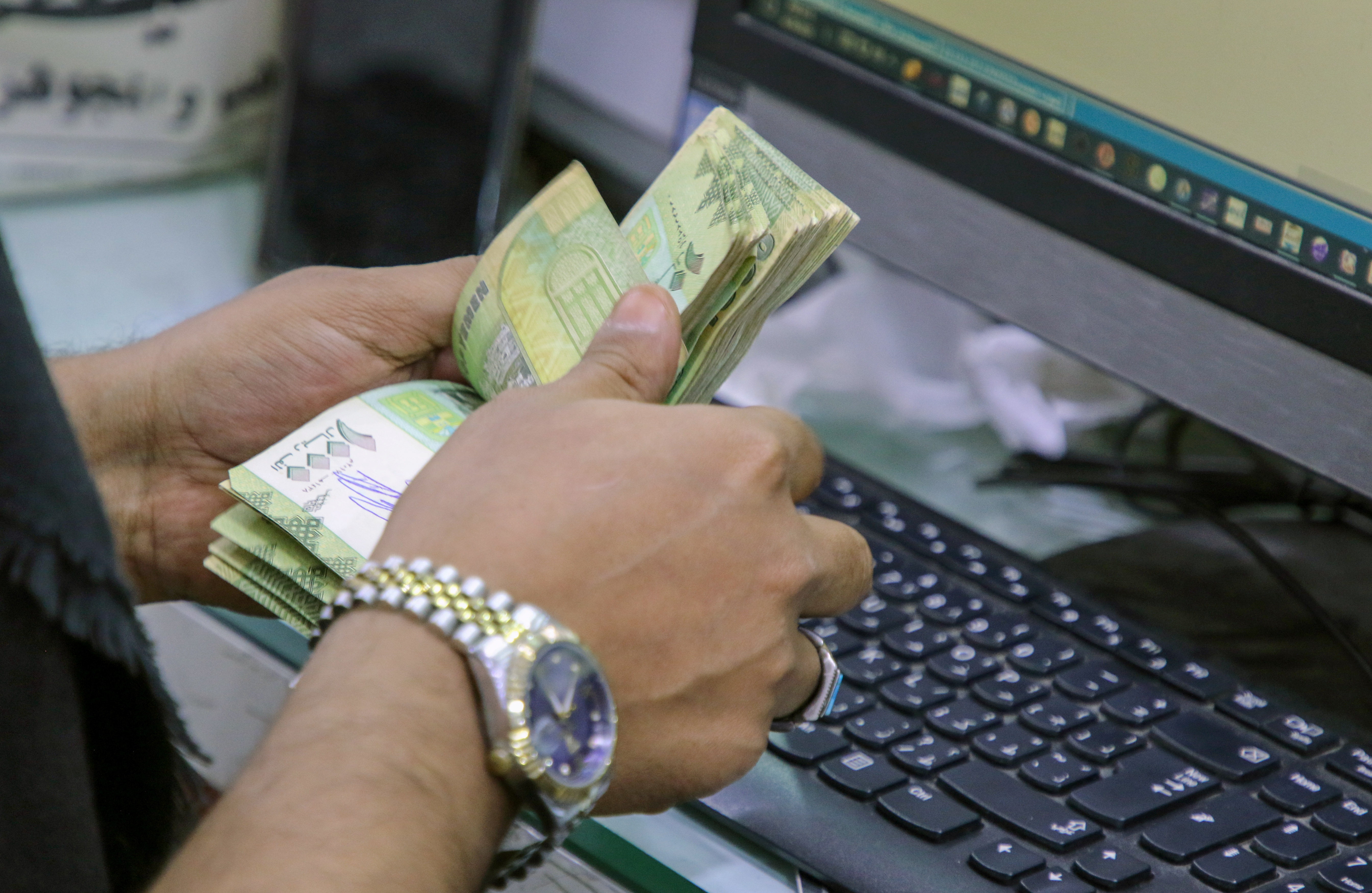 أمين صندوق يعد أوراق نقدية من الريال اليمني في محل صرافة محلي في عدن، اليمن، 29 يونيو 2021. (صورة من أرشيف رويترز)