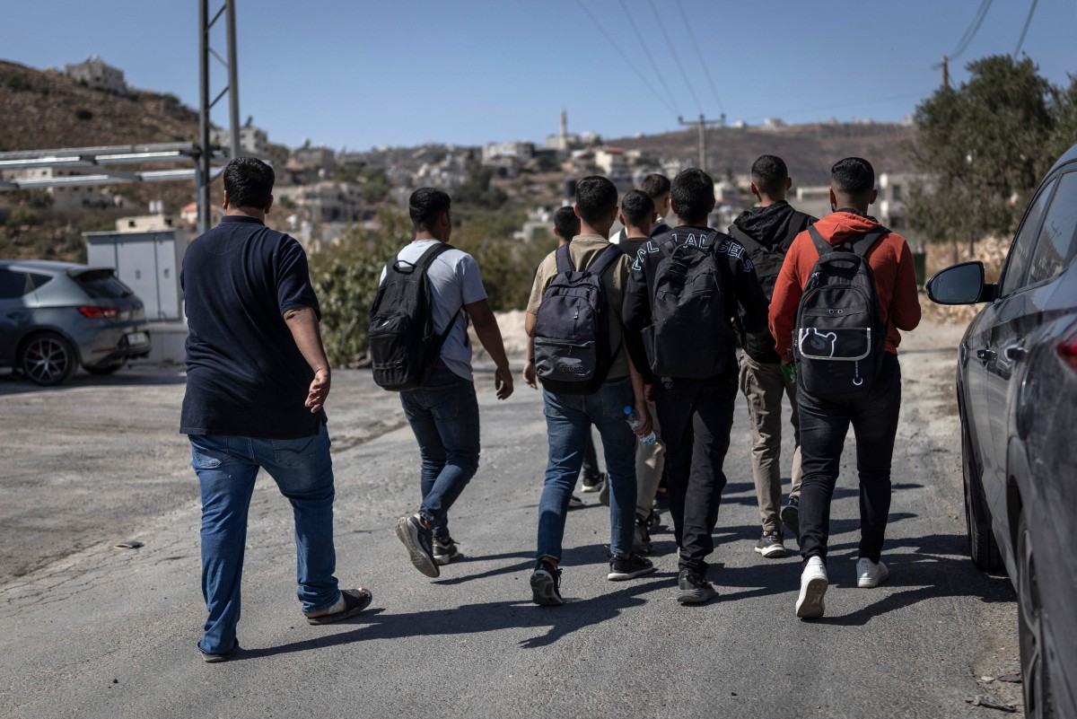 School students walk along the road between al-Mughayyir and Abu Falah villages near Ramallah in the Israeli-occupied West Bank, on October 4, 2026. (AFP)