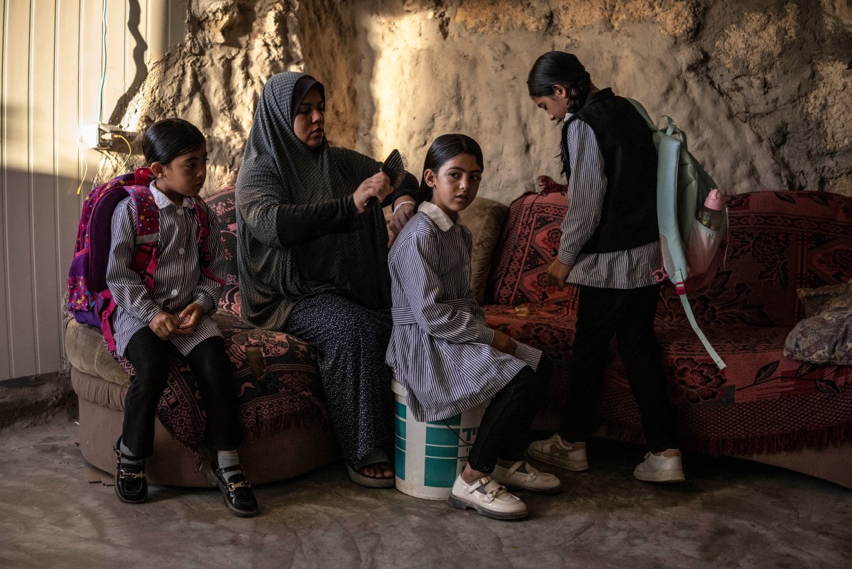 Arwa Amr brushes her daughter Layan’s hair before school in their cave home in Al-Tuwani, in the Israeli-occupied West Bank, on Sept. 16, 2026. The family moved into caves after Israeli forces destroyed their home in 2023. (AFP)