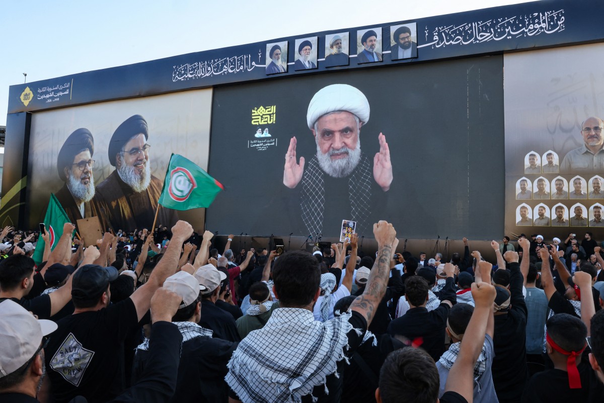 Hezbollah supporters shout slogans as they watch a televised speech by Hezbollah chief Naim Qassem in Beirut's southern suburbs on September 27, 2026. (AFP)