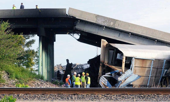 US highway buckles after rail cars hit overpass