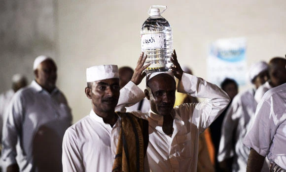Departing pilgrims face cap on Zam Zam water