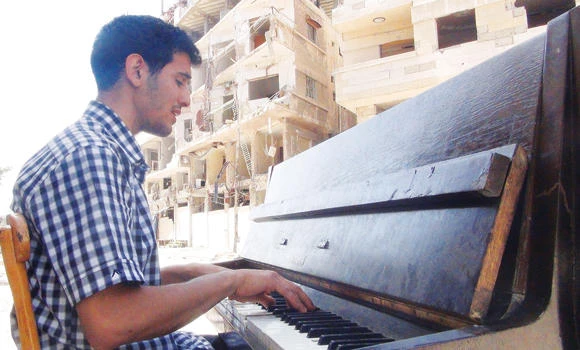 His piano burned by Daesh, Syrian musician joins migrant tide