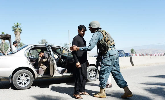 An Afghan policeman (R) searches a passenger in the city of Jalalabad, close to the border with Pakistan, on Friday, after reports that an aid worker from Perth has been kidnapped by armed men in Jalalabad. (AFP)