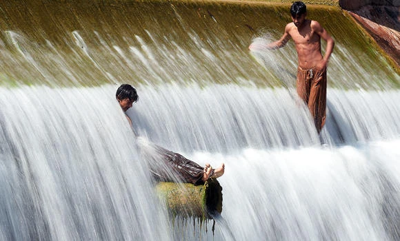 Pakistani youths cool off in a stream during hot weather on the outskirts of Islamabad on Friday. (AFP)