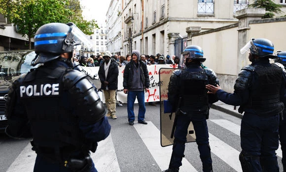 French CRS anti-riot police stand facing protesters and migrants who have occupied a high school in Paris' nineteenth district during a demonstration to call for better living conditions in Paris on Friday. (AFP)