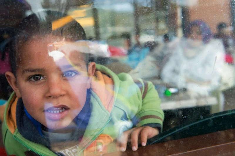 INNOCENCE: A boy looks out through a window at refugee camp in Idomeni, near the Greek-Macedonian border, on Saturday. (AFP)