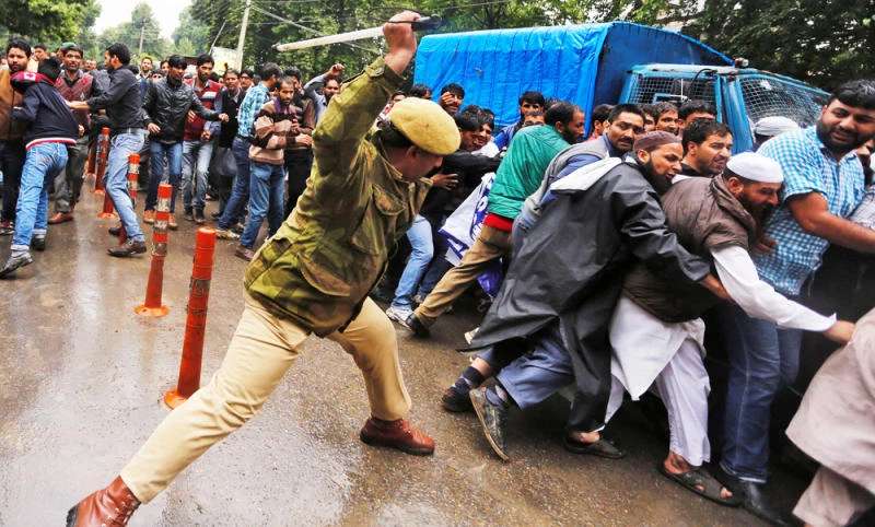 An Indian policeman uses a baton to disperse demonstrators during a protest by government employees demanding their long pending arrears and a regularisation of their temporary jobs, according to protesters, in Srinagar, on Tuesday. (REUTERS)