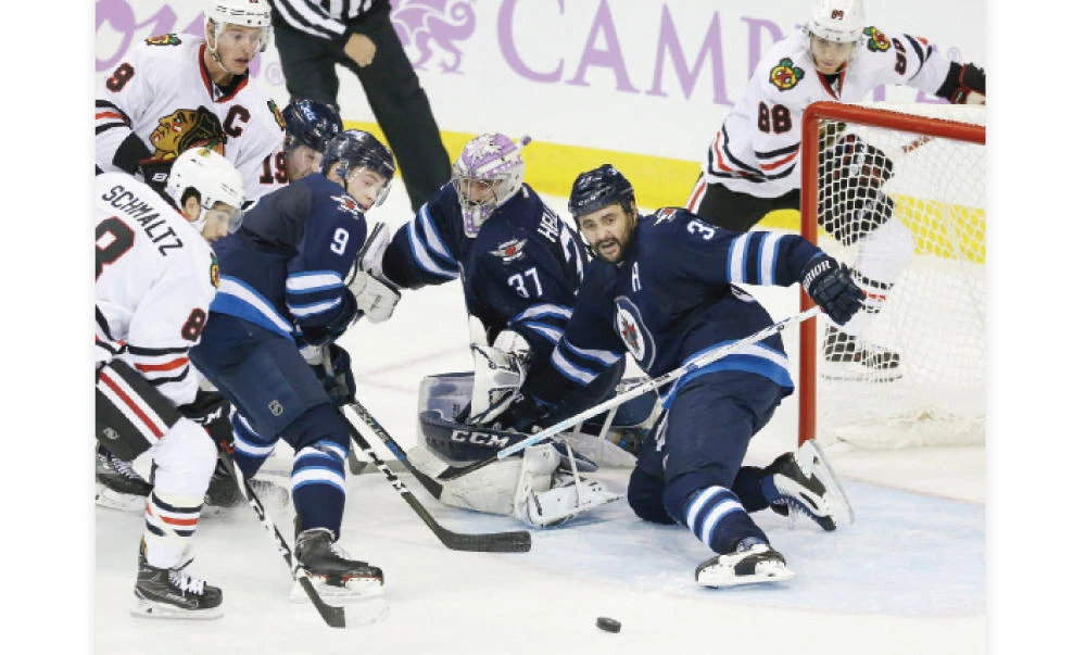 GOAMOUTH SCRAMBLE: Winnipeg Jets defenseman Dustin Byfuglien (33) helps Winnipeg Jets goalie Connor Hellebuyck (37) make a save during the second period against the Chicago Blackhawks at MTS Centre on Tuesday. (USA TODAY Sports)