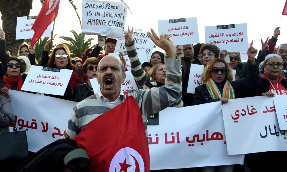 Tunisians shout slogans during a demonstration outside parliament in Tunis on Saturday against allowing Tunisians who joined the ranks of jihadist groups to return to the country. The writing in Arabic reads: ''we are all under threat by terrorism''. (AFP / FETHI BELAID)