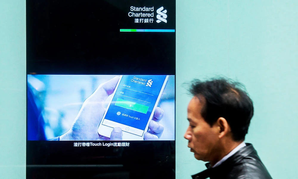 A pedestrian walks past a Standard Chartered sign in the Central district of Hong Kong on February 24, 2017. (AFP)