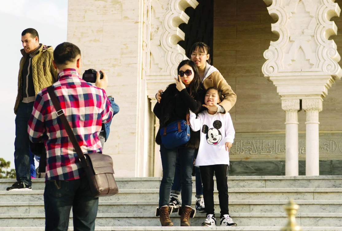 Asian tourists pose for a photo as they visit the Hassan Tower in Rabat. (AFP)